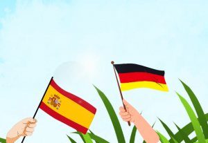 Spanische und deutsche Flagge im blauen Himmel